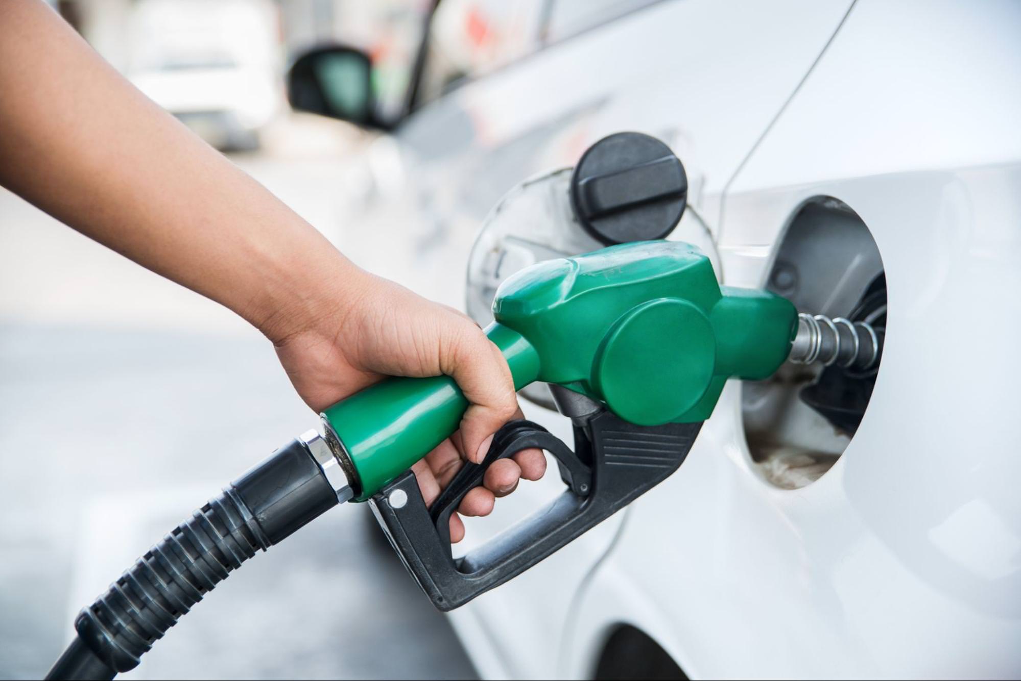 zblízka ruky držící zelenou palivovou trysku k doplnění paliva do auta
