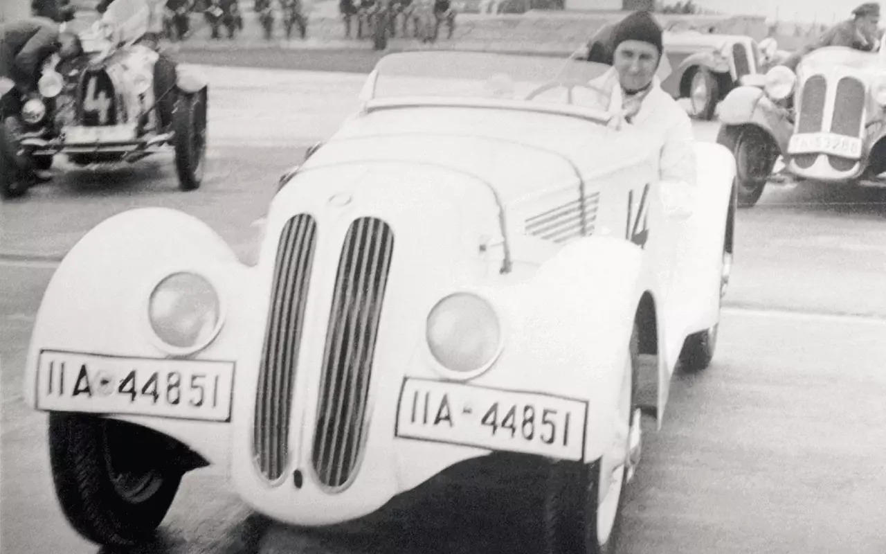 Vintage black and white photograph of the iconic BMW 328 racing car with a driver visible in the cockpit.