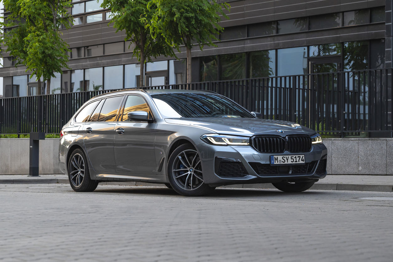Na tomto obrázku je BMW řady 5 kombi (známé také jako model Touring). Vůz je stříbrné nebo šedé barvy a stojí na ulici v městském prostředí.