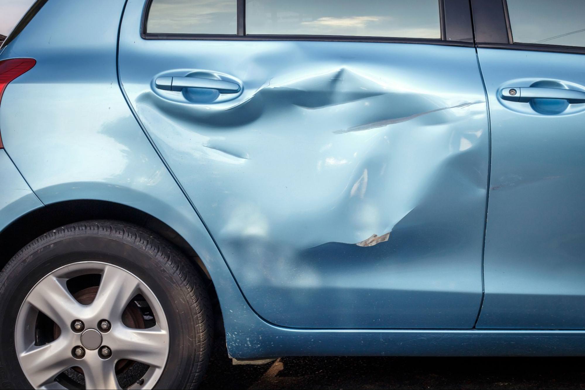 boční pohled na modré auto s poškozením při nehodě na pravé straně