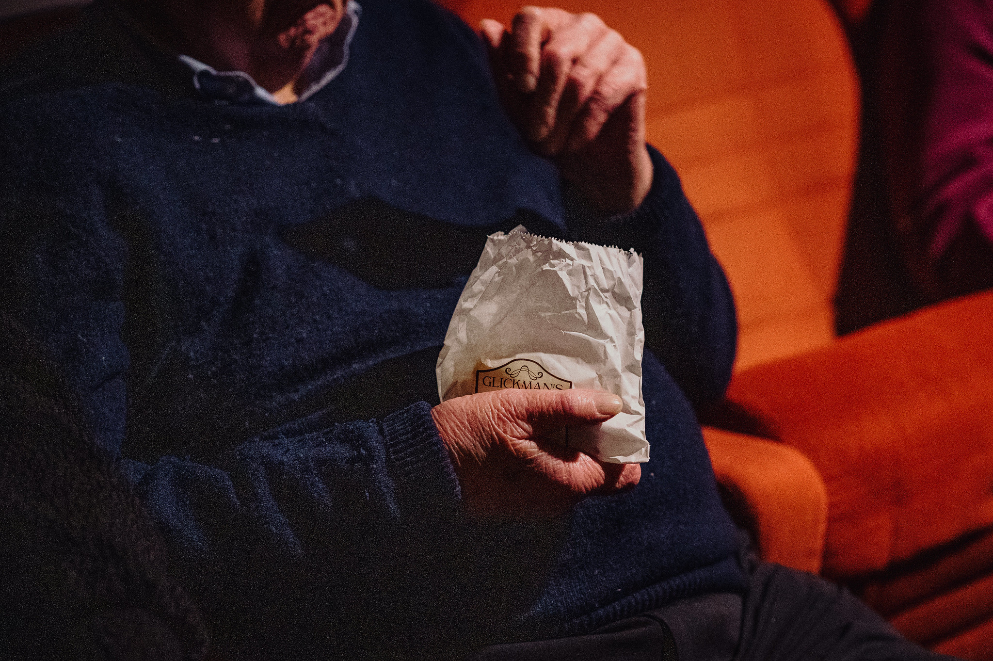 Gentleman sitting in cinema holding a bag of Glickman's sweets