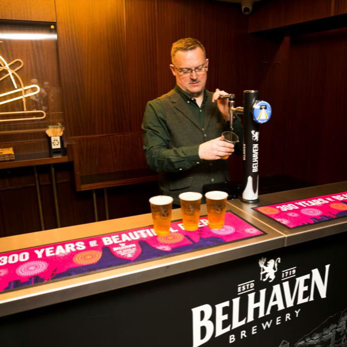Barman pouring Belhaven beer from a tap featuring Glasgow Film Festival branding