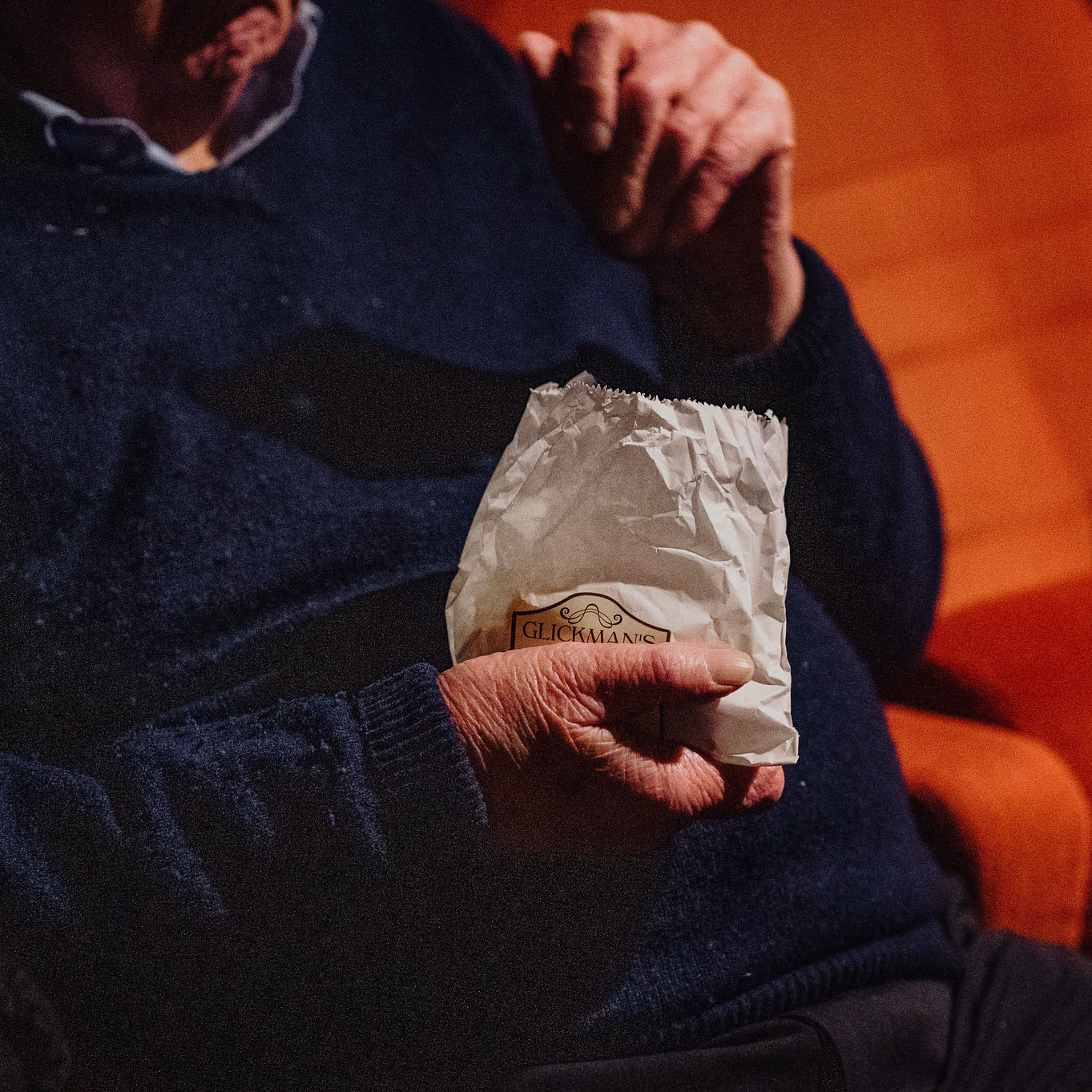 Gentleman sitting in cinema holding a bag of Glickman's sweets
