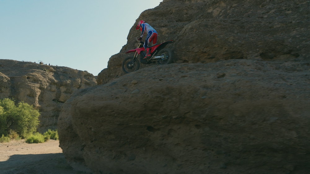 A rider on the Stark VARG EX cresting a massive boulder ridge.