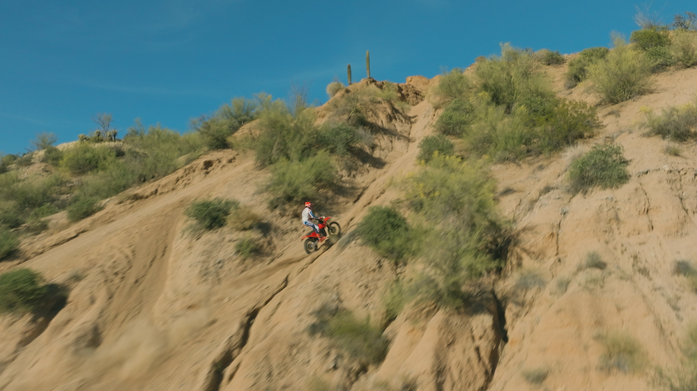 Top-down aerial of a single rider on the VARG EX picking a line across rugged Arizona canyon ridges.